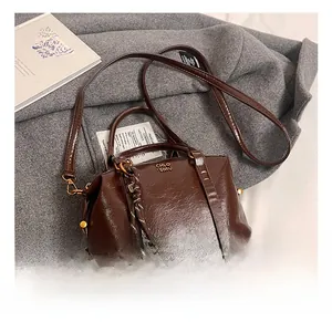 Detailed view of dark brown oil wax leather Boston bag with gold rivets and logo