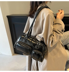 Detail of a black glossy shoulder bag with multiple zippers and silver hardware