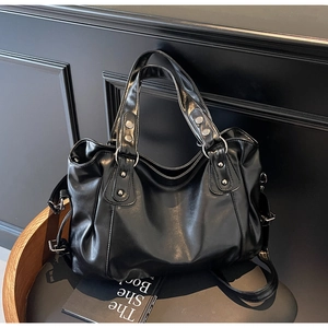 Détail d'un sac cabas en cuir noir brillant avec garnitures argentées sur une chaise en bois