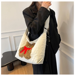 Detail of white quilted tote bag featuring a cute brown plush bear charm and ribbon