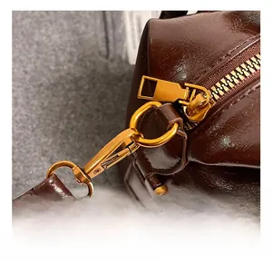 Detail of dark brown glossy leather bag featuring high-quality gold metal hook and zipper