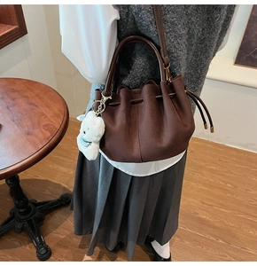 Gros plan du sac seau en daim marron avec cordon de serrage et breloque lapin en peluche