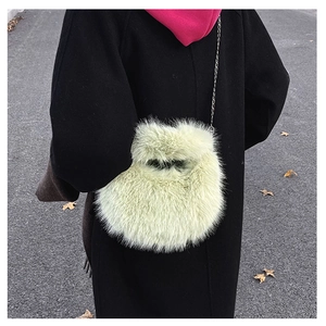 Dettaglio di una borsa in pelliccia sintetica con catena sottile su un cappotto nero