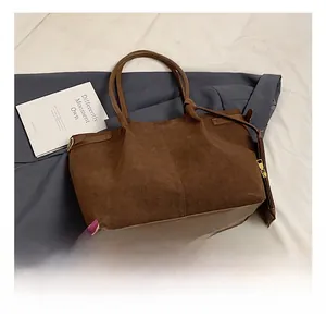 Detailed view of brown suede tote bag featuring matte texture and golden hardware