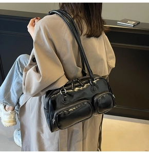Detail view of black glossy shoulder bag with silver hardware and front zip pockets