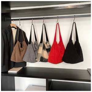 Primer plano de bolsos tote de lana en varios colores en un estante de metal negro