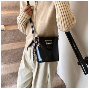 Détail du sac seau en cuir noir avec pendentif étoile et boucle ondulée sur l'escalier