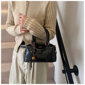 Detail of vintage black shiny leather bowling bag with gold bell charm and branding