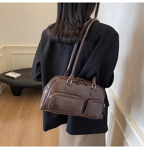 Detail of dark brown patent leather shoulder bag with silver zippers on a model