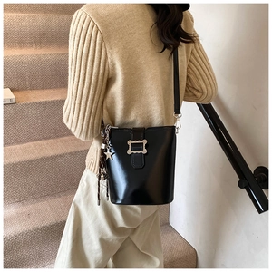Détail du sac seau noir vintage avec breloque étoile et boucle métallique porté par mannequin
