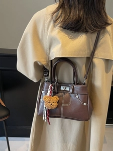 Vintage brown leather crossbody bag with stitching details and plush bear charm