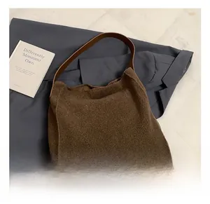 Detalle del bolso tote de felpa marrón oscuro con correa de cuero y estilo urbano