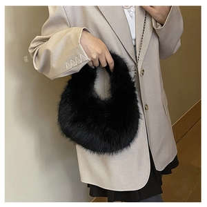 Dettaglio borsa hobo in ecopelliccia nera con tracolla a catena su blazer beige