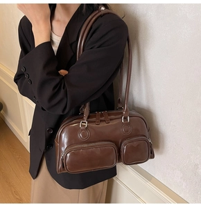 Close-up of a dark brown vintage leather shoulder bag with side zipper pockets on a model