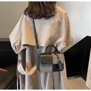 Détail d'un sac bandoulière bicolore en tweed et cuir porté par un mannequin en extérieur