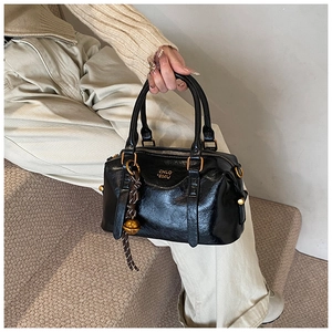 Detail of black vintage leather bowling bag with gold logo and woven ball pendant