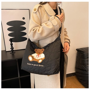 Detail of black quilted tote bag with heart patterns and cute bear embroidery