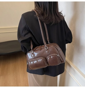 Deep brown bowling shoulder bag with dual front zippers shown on model for size scale