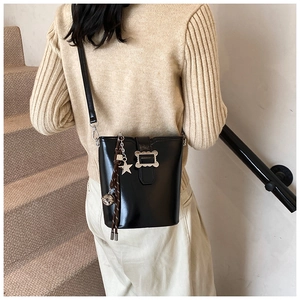 Détail d'un sac seau noir brillant avec boucle argentée et pendentifs en forme d'étoile