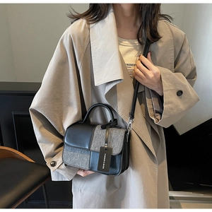 Détail d'un sac bandoulière en tweed gris et cuir noir porté avec un trench-coat