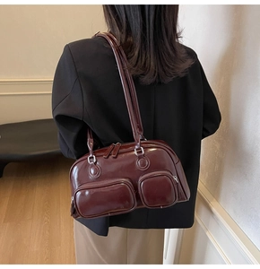 Detail of burgundy leather shoulder bag with two front zipper pockets and glossy finish
