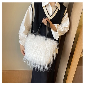 Gros plan sur un sac cabas en peluche blanche avec des anses en cuir noir contrastées
