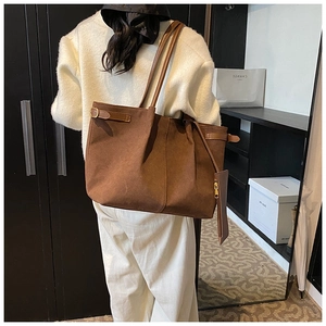 Détail d'un sac cabas en daim marron avec boucles latérales et pochette assortie
