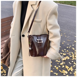 Détails d'un sac seau en cuir marron avec des breloques cloche et étoile en argent