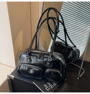 Detail view of black faux leather bowling bag with silver zippers and reflective surface