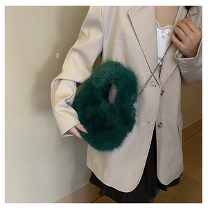 Dettaglio borsa a mano in peluche verde scuro con tracolla a catena dorata