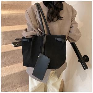 Detail van de zwarte grote shopper met binnentas en dunne bandjes op zakelijke kleding