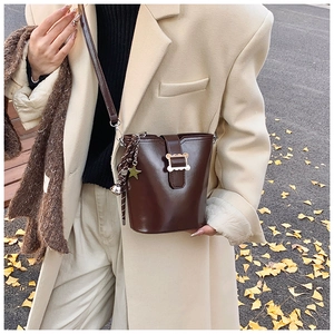 Détail du sac seau en cuir marron foncé avec boucle dorée et pendentif étoile cloche