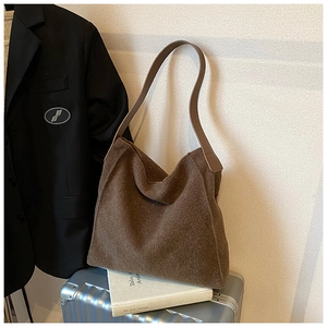 Detalle del bolso tote de lana marrón oscuro sobre maleta que muestra la textura