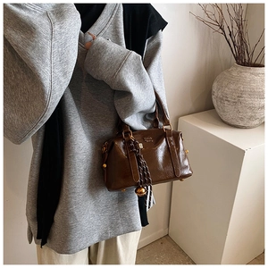 Detail of vintage brown glossy leather bowling bag with decorative pendant and logo