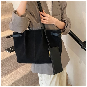 Detailopname van zwarte tote bag met gouden zijgespen en bijpassend zakje met ritssluiting