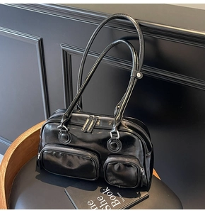 Close-up of black glossy bowling shoulder bag with double straps and two front zip pockets