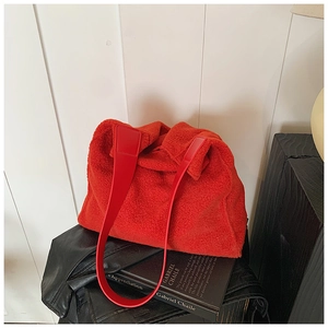 Detalle del bolso tote rojo de pelo sintético con textura suave y asas de cuero