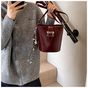 Détail du sac seau en cuir brillant rouge foncé avec boucle argentée et breloque étoile