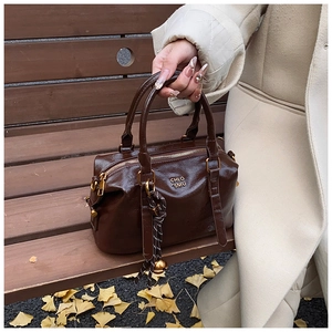 Detailed close-up of a vintage brown leather bowling bag with gold zipper and lucky charm