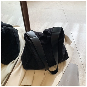 Detalle de la textura de lana negra suave y la correa de hombro de cuero liso del bolso tote