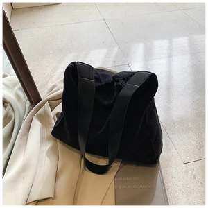Detalle del bolso tote negro de felpa con textura suave y correas de piel lisa