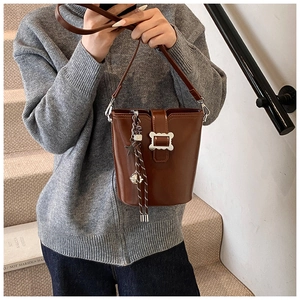 Vue détaillée d'un sac seau vintage en cuir marron avec boucle argentée et pendentif
