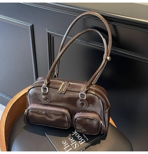 Detail of dark brown vintage oil-wax leather shoulder bag with silver zippers and dual pockets