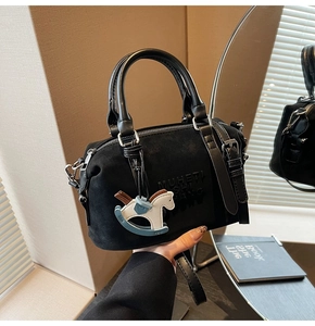 Detail of vintage black suede Boston bag with leather handles and rocking horse charm