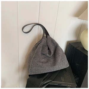 Detalle del bolso tote de lana gris con textura de fieltro y correa de hombro ancha negra