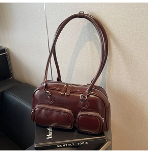 Deep red glossy leather bowling bag with side zipper pockets and long shoulder straps