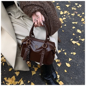 Detail of vintage dark brown faux leather bowling bag with gold hardware on autumn leaves