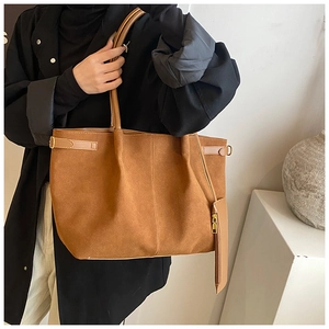 Detailweergave van grote bruine suède tote bag met metalen gesp en klein ritszakje