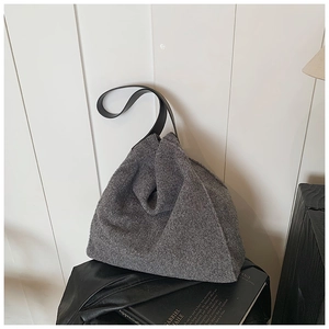 Detalle de bolso tote de lana con pliegue de origami y correa de cuero negro