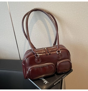 Close-up of shiny dark red oil wax leather shoulder bag with silver hardware detail